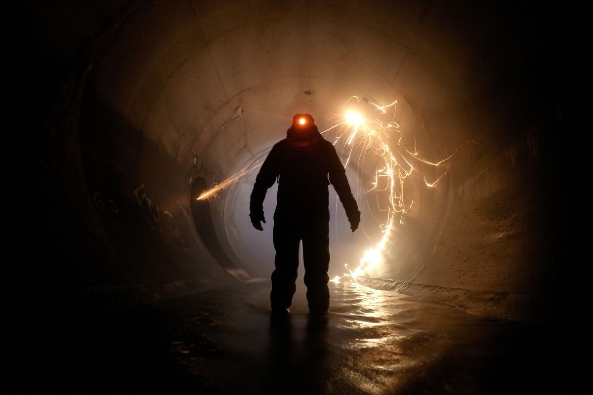 Worker in protective gear inside a storm drain