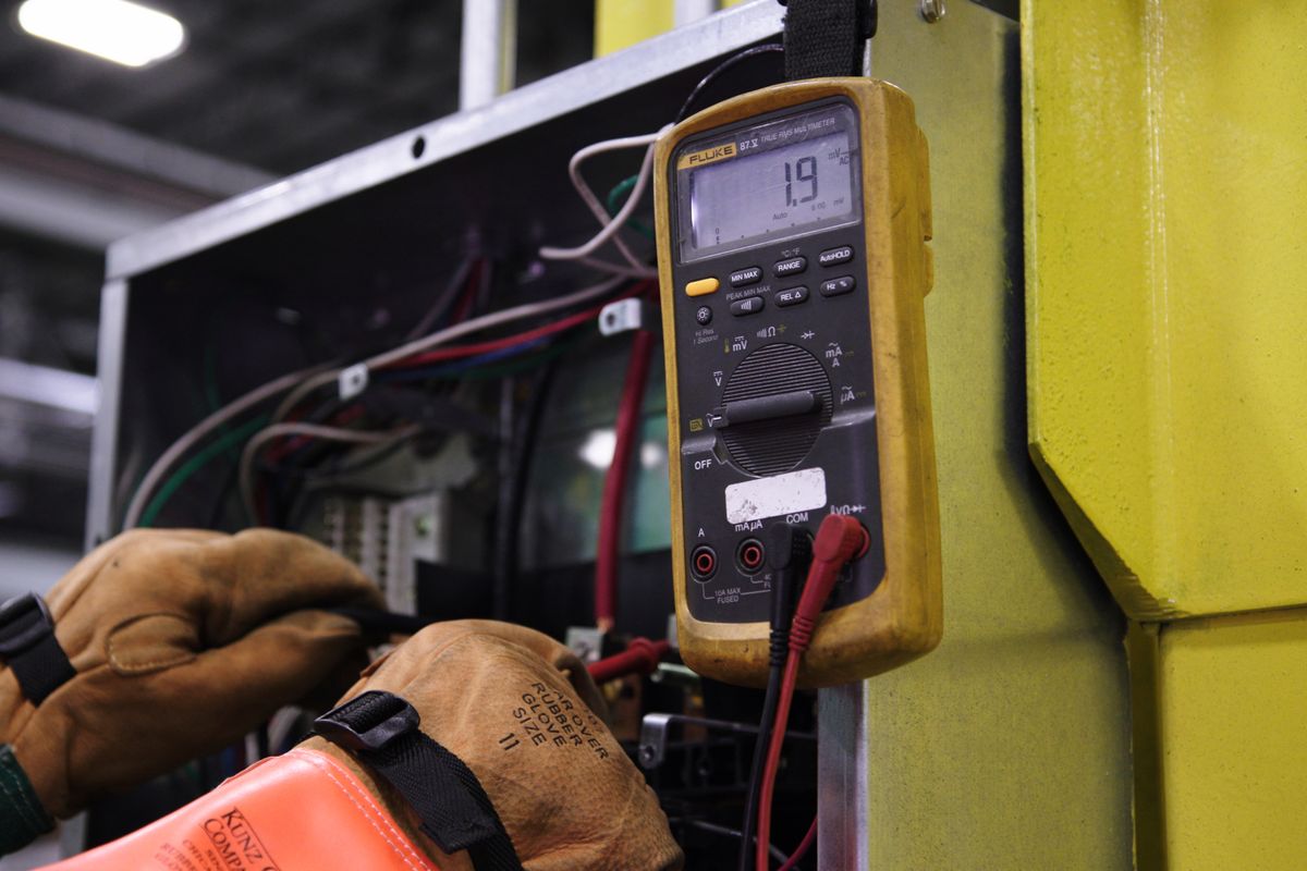Electrician testing a control panel with a multimeter